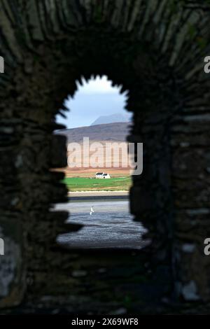 Kilnave Spätmittelalterliche Kapelle in Gruinart Bay, Islay, Innere Hebriden, Schottland. Blick durch das Fenster auf die Farm in Killinallan Stockfoto