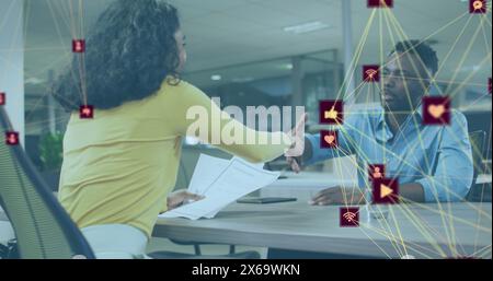 Bild von vernetzten Symbolen, die Kugeln über verschiedenen Kollegen bilden, die diskutieren und die Hände schütteln Stockfoto