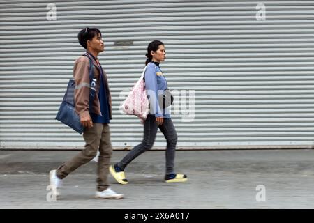 SAMUT PRAKAN, THAILAND, 16. März 2024, Ein Paar geht den Bürgersteig neben einer Metallwand entlang Stockfoto