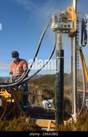 HAUPIRI, NEUSEELAND, 7. MAI 2024: Bohrer betreiben ein tragbares Bohrgerät, um ein 10 Meter langes Loch auf dem Gipfel des Mount Morgan mit Blick auf das Haupiri Valley an der Westküste Neuseelands zu versenken. Das Loch wird für seismische GPS-Überwachungsinstrumente verwendet, um die Bewegung entlang der Alpenverwerfung zu messen, die sich in der Nähe des Berges befindet. Die gesamte Bohrausrüstung einschließlich Luftkompressor, Generator und Bohrgerät wurde per Hubschrauber zum Gipfel geflogen. Stockfoto