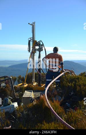 HAUPIRI, NEUSEELAND, 7. MAI 2024: Bohrer betreiben ein tragbares Bohrgerät, um ein 10 Meter langes Loch auf dem Gipfel des Mount Morgan mit Blick auf das Haupiri Valley an der Westküste Neuseelands zu versenken. Das Loch wird für seismische GPS-Überwachungsinstrumente verwendet, um die Bewegung entlang der Alpenverwerfung zu messen, die sich in der Nähe des Berges befindet. Die gesamte Bohrausrüstung einschließlich Luftkompressor, Generator und Bohrgerät wurde per Hubschrauber zum Gipfel geflogen. Stockfoto