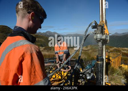 HAUPIRI, NEUSEELAND, 7. MAI 2024: Bohrer betreiben ein tragbares Bohrgerät, um ein 10 Meter langes Loch auf dem Gipfel des Mount Morgan mit Blick auf das Haupiri Valley an der Westküste Neuseelands zu versenken. Das Loch wird für seismische GPS-Überwachungsinstrumente verwendet, um die Bewegung entlang der Alpenverwerfung zu messen, die sich in der Nähe des Berges befindet. Die gesamte Bohrausrüstung einschließlich Luftkompressor, Generator und Bohrgerät wurde per Hubschrauber zum Gipfel geflogen. Stockfoto