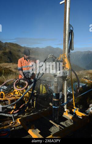 HAUPIRI, NEUSEELAND, 7. MAI 2024: Bohrer betreiben ein tragbares Bohrgerät, um ein 10 Meter langes Loch auf dem Gipfel des Mount Morgan mit Blick auf das Haupiri Valley an der Westküste Neuseelands zu versenken. Das Loch wird für seismische GPS-Überwachungsinstrumente verwendet, um die Bewegung entlang der Alpenverwerfung zu messen, die sich in der Nähe des Berges befindet. Die gesamte Bohrausrüstung einschließlich Luftkompressor, Generator und Bohrgerät wurde per Hubschrauber zum Gipfel geflogen. Stockfoto