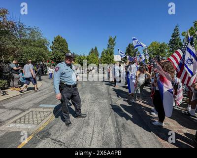 Palo Alto, Kalifornien, USA, 12. Mai 2024. Hunderte von Juden werden von Hindus, Muslimen, Chinesen und anderen Verbündeten bei einer Gegenveranstaltung an der Stanford University am Israel Unabhängigkeitstag und Muttertag bei einer interreligiösen Kundgebung begleitet, die von einer jüdischen Studentengruppe organisiert wird. Dies geschah am Ende des Weißen Platzes, wo propalästinensische Demonstranten ein Zeltlager aufgebaut und eine Kundgebung abgehalten haben, bei der sie "Intifada" gegen Israel forderten, sich über die Juden lustig machten und erklärten: "Wir werden den Krieg gewinnen". Ein Polizist hält die beiden Gruppen getrennt und steht in der Mitte zwischen ihnen. (Kreditbild: Stockfoto