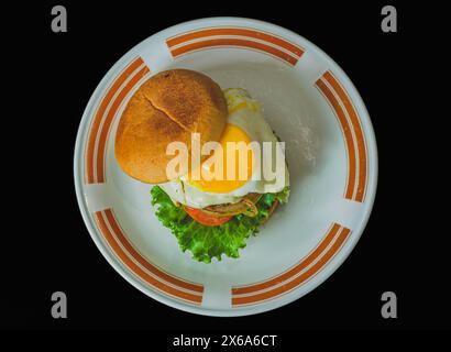 Ein saftiges hausgemachtes Hamburger-Patty mit einer sonnigen Seite auf Spiegeleier. Der Burger ist auf einem weißen Teller. Stockfoto