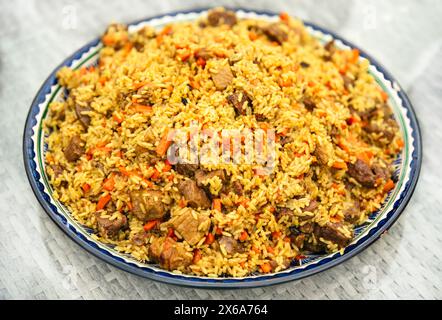 Nationalgericht der orientalischen Küche der zentralasiatischen Länder Pilaf (Plov) mit Schweinefleisch und Rindfleisch auf dem Teller Stockfoto