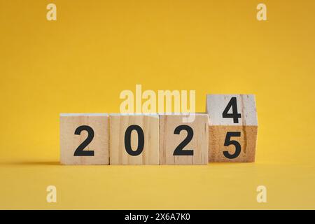 Von 2024 bis 2025, Zahlen auf Holzblöcken. Auf gelbem Hintergrund, Neujahrskonzept. Stockfoto