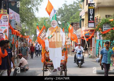 Varanasi, Indien. Mai 2024. Die Leute laufen neben einem Ausschnittplakat des indischen Premierministers Narendra Modi vor dem Start seiner Roadshow (Foto: Prabhat Mehrotra/SOPA Images/SIPA USA) Credit: SIPA USA/Alamy Live News Stockfoto