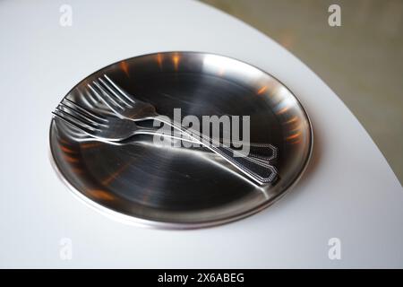 Edelstahlplatte und Gabel auf weißem Tisch Stockfoto