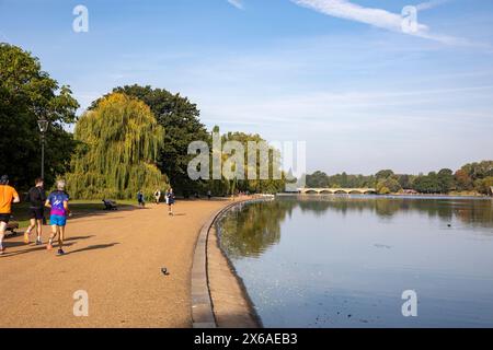 Hyde Park London, Männer, die entlang der Serpentine Shore joggen, am frühen Morgen an einem September Hitzewelle Tag laufen, London, England, UK 2023 Stockfoto