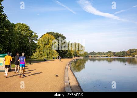 Hyde Park London, Männer, die entlang der Serpentine Shore joggen, am frühen Morgen an einem September Hitzewelle Tag laufen, London, England, UK 2023 Stockfoto