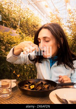 Südisland-2. märz 2023: kaukasische Touristenfrau isst Muscheln in Fridheimar - Besucherfreundliche Tomatenfarm und Restaurant in Fridheimar Stockfoto