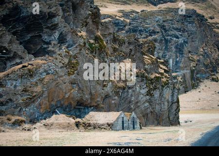 Rasenhaus am Fuße des Drangurinn Rock in Südisland. Eyjafjll Berge im Süden Islands nahe der Ringstraße, Route 1. Turfhouses, die mit Elfen verbunden sind, Stockfoto