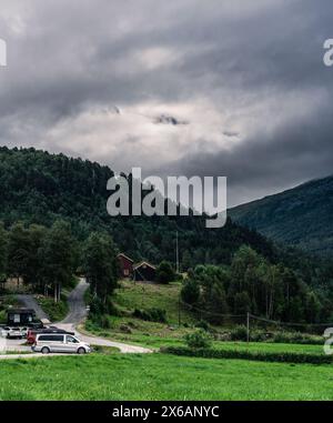 Autos parken auf dem Innerdalen-Nationalpark-Parkplatz mit den Trollheimen-Gebirgszügen, die nachmittags von weißen Wolken bedeckt sind. Møre og Romsdal in Norwegen Stockfoto