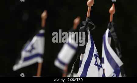 JERUSALEM – 12. MAI: Israelische Nationalflaggen mit schwarzen Trauerbändern sitzen auf dem jüdischen Friedhof im Ölberg über den Gräbern gefallener israelischer Soldaten, während sich das Land auf den Gedenktag des Yom Hazikaron für die gefallenen Soldaten am 12. Mai 2024 in Jerusalem vorbereitet. Israel Stockfoto