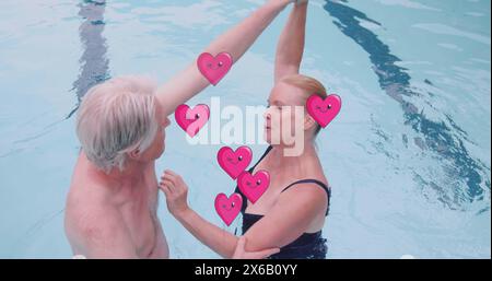 Bild von Herzsymbolen über dem kaukasischen Seniorenpaar, das im Pool tanzt Stockfoto