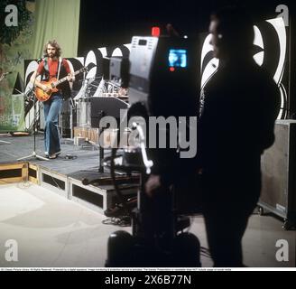 Mode der 1970er Jahre Ein junger Mann, der die typische Mode der 1970er Jahre trägt, eine Hose mit breiten Beinen. Eine Hose mit dem Namen Bell-Bottoms oder Flares, die von den Knien bis nach unten breiter wird und eine glockenartige Form des Hosenbeins bildet. Er ist Musiker Claes af Geijerstam mit seiner Band Marsfolket in einem tv-Studio und nimmt ein Programm auf. 1971. Svahn Stockfoto