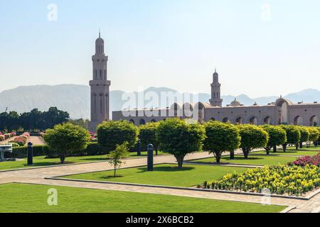 Ein malerischer Blick auf eine große Moschee, umgeben von üppigem Grün und blühenden Blumen, vor dem Hintergrund ferner Berge unter der klaren Ske Stockfoto