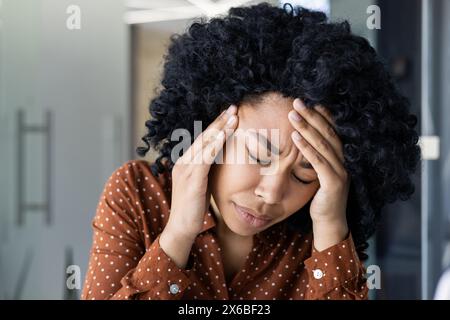 Junge Frau, die Stress hat und den Kopf in den Händen hält, während sie vom Home Office aus arbeitet. Konzept von Stress, Kopfschmerzen, Müdigkeit und Herausforderungen am Arbeitsplatz. Stockfoto