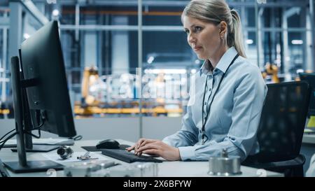 Autowerkstatt: Porträt einer selbstbewussten Chefingenieurin, die am Desktop-Computer arbeitet. Professioneller Techniker in der Herstellung von automatisierten Roboterarmen in der Fertigung von High-Tech-Elektrofahrzeugen Stockfoto
