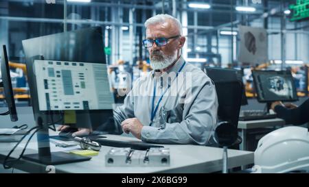 Autowerkstatt: Porträt eines leitenden männlichen Chefingenieurs, der an Desktop-Computern in automatisierten Roboterarmmontageanlagen arbeitet, die High-Tech-Elektrofahrzeuge herstellen. Förderband Für Elektronikproduktion Stockfoto