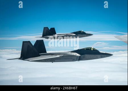 Wo F-22 Raptoren, die der 477th Fighter Group zugeordnet sind, fliegen in Formation mit einem KC-135 Stratotanker, der dem 92nd Air Betanking Wing während der Übungen zugeteilt wurde Stockfoto