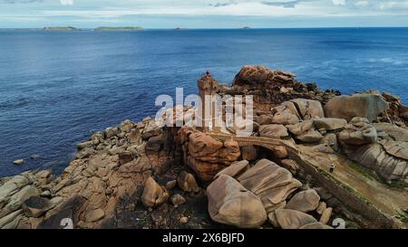 Drohnenaufnahmen des Phare de Men Ruz Ploumanac'h Perros-Guirec Frankreich, des ikonischen rosa Granit-Leuchtturms, der auf zerklüfteten Felsformationen thront Stockfoto