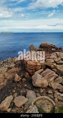 Drohnenaufnahmen des Phare de Men Ruz Ploumanac'h Perros-Guirec Frankreich, des ikonischen rosa Granit-Leuchtturms, der auf zerklüfteten Felsformationen thront Stockfoto