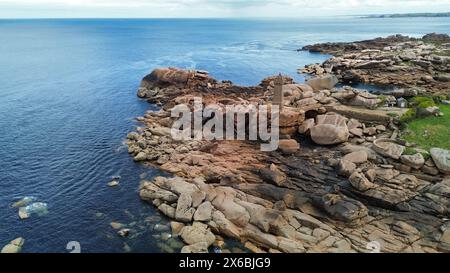 Drohnenaufnahmen des Phare de Men Ruz Ploumanac'h Perros-Guirec Frankreich, des ikonischen rosa Granit-Leuchtturms, der auf zerklüfteten Felsformationen thront Stockfoto