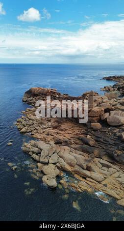 Drohnenaufnahmen des Phare de Men Ruz Ploumanac'h Perros-Guirec Frankreich, des ikonischen rosa Granit-Leuchtturms, der auf zerklüfteten Felsformationen thront Stockfoto