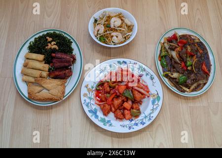 Chinesisches Essen: King Garnelen Chow mein, süß-saures Huhn, Rindfleisch in schwarzer Bohnensoße und gemischte Vorspeisen mit Rippchen, Krabbentoast, Meeresgras und Frühlingsrollen Stockfoto