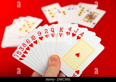 Karten spielen. Pokerkarten in der Hand eines Enthusiasten. Brettspiel. Isoliert auf rotem Hintergrund. Stockfoto