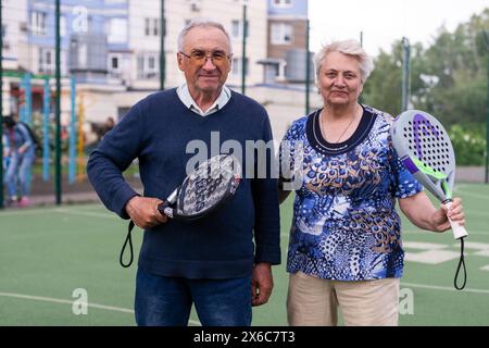 Ukraine, Kiew, 05. Mai 2024, glückliche fröhliche positiv lächelnde Padel-Spieler verschiedener Generationen posieren auf dem Padel-Hof Stockfoto