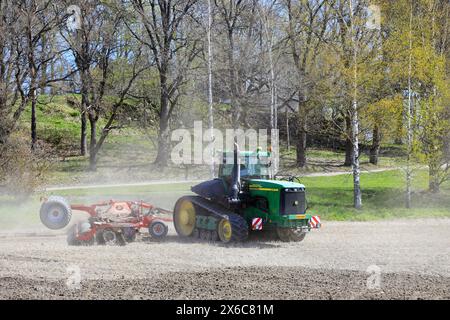 Arbeiten mit John Deere 9520T Raupenschlepper und Horsch Scheibenegge im Stoppelfeld an einem Frühlingstag. Salo, Finnland. Mai 2024. Stockfoto