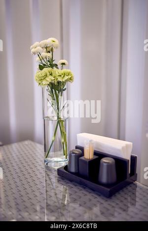 Weiße und grüne Chrysanthemen auf dem Tisch neben Servietten im Café Stockfoto