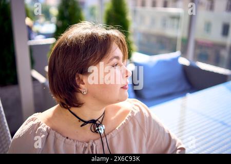 Eine mittelgroße Frau in pfirsichfarbenem Kleid mit einem Glas Wasser im Restaurant Stockfoto