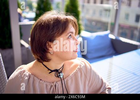 Eine mittelgroße Frau in pfirsichfarbenem Kleid mit einem Glas Wasser im Restaurant Stockfoto