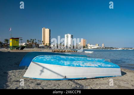 Ein umgedrehtes Schlauchboot, im Vordergrund des Bildes, am sonnigen Tag an einem spanischen Strand gelegen. Stockfoto