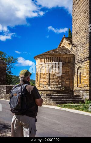 Einsamer männlicher Wanderer, der auf der Straße spaziert und die Gelegenheit nutzt, einige Sehenswürdigkeiten zu Unternehmen, indem er ein altes romanisches Denkmal auf dem Weg besucht Stockfoto