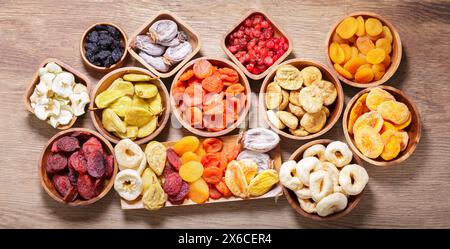 Schüsseln mit verschiedenen getrockneten Früchten auf Holztisch, Blick von oben Stockfoto