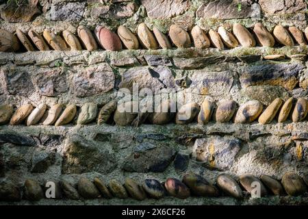 Eine alte Mauer aus Steinen und Kies, die an die Vegetation ausgerichtet ist. Stockfoto