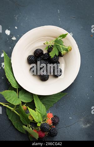 Wilde Himbeeren aus schwarzem Wald in einer Tonschale auf einem alten Holztisch Stockfoto