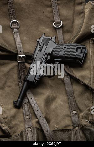 Deutsche Vintage-9-mm-Pistole aus dem Zweiten Weltkrieg. Hintergrund eines alten Militärrucksacks aus Leinwand. Stockfoto