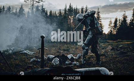 Dark Age Battlefield: Brutaler Kampf um zwei gepanzerte mittelalterliche Ritter, die Feinde mit Schwert töten. Die Schlacht der bewaffneten Krieger. Dramatische Szene, filmischer Rauch, Licht in historischer Nachstellung Stockfoto