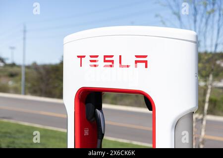 Nahaufnahme einer weiß-roten Tesla-Ladestation auf einem Parkplatz ohne Fahrzeuge. Stockfoto