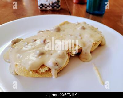 Herzhafte Biscuits and Gravy (Brötchen mit Soße) auf weißer Platte, Blick auf Augenhöhe Stockfoto