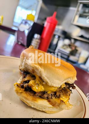 Saftiger Cheeseburger auf Teller im Diner-Setting, Nahaufnahme Stockfoto