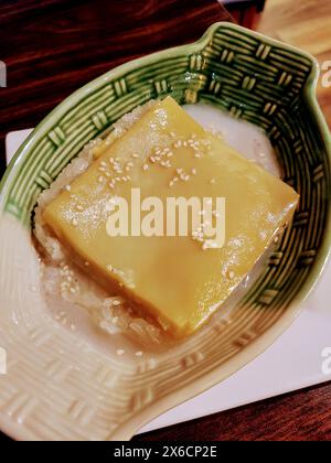 Nahaufnahme des asiatischen Desserts mit Mango-Pudding-Reis in grüner Keramikschale Stockfoto