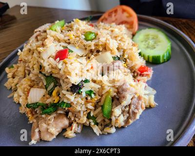 Moderner gebratener Reis mit Fleisch und Gemüse auf Holztisch, Blick auf Augenhöhe Stockfoto