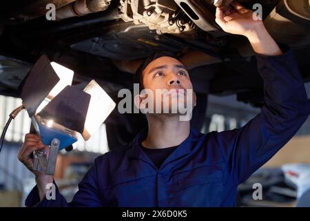 Mensch, Mechaniker und Inspektion unter Auto, Reparaturwerkstatt und Fahrzeugtechnik für die Fahrzeugwartung. Professionelle Fahrzeugaufzüge und Motorwartung Stockfoto